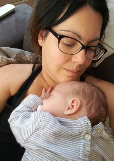 a woman in glasses and a black top hat is holding a baby