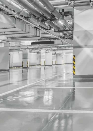 Jasny, pusty parking podziemny z gładką, odbijającą światło posadzką i filarami.