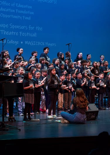 A youth choir performing on stage at the Central Valley Theatre Festival with a Baldwin piano.
