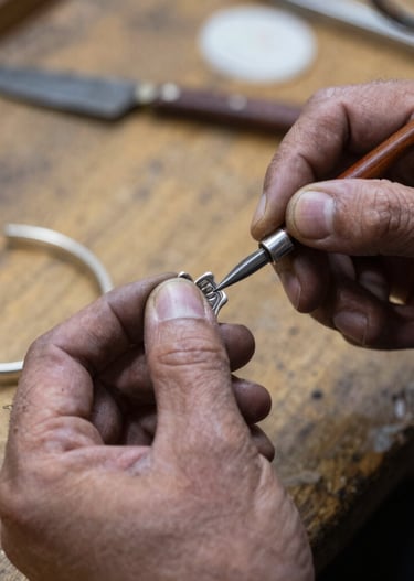 Artisan carefully shaping silver jewelry in a minimalist, softly lit workshop.