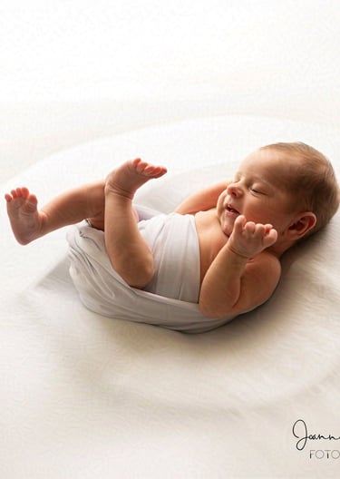 Maleństwo owinięte w delikatny owijacz sesja noworodkowa w studio.