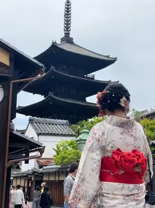 Woman in white kimono with red obi standing before Yasaka Pagoda in Kyoto