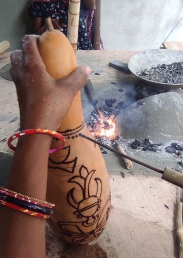 Tribal artisan engraving design on a gourd using hot iron