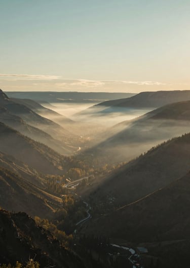 A wide-angle landscape of a misty North American / US valley at sunrise, sophisticated teal gray and muted gold tones, serene and modern photography.