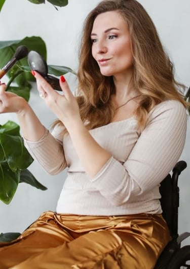 Women in a wheelchair applies makeup to her face