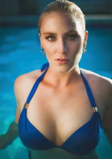 A girl in a blue string bikini in the pool staring straight 