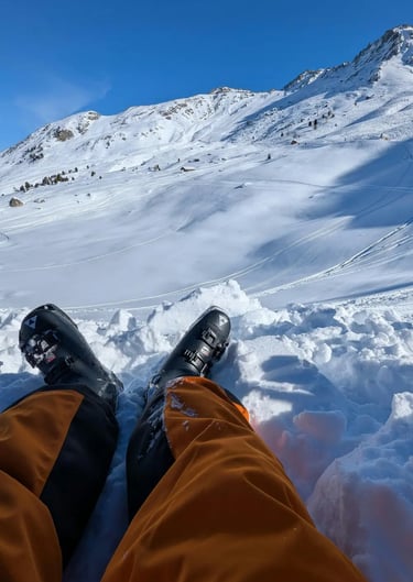 Relaxed skier sitting with boots stretched out, overlooking snowy alpine mountains