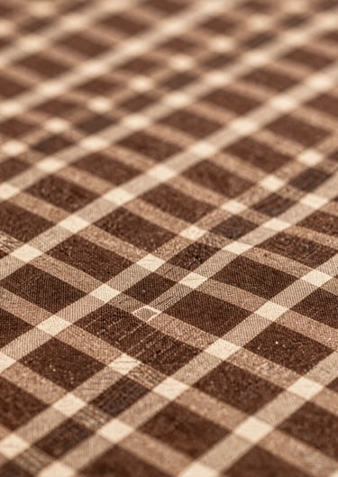 A macro shot of a traditional Nigerian textile with a modern geometric twist, using #8D765D and #3D2C20 silk threads.