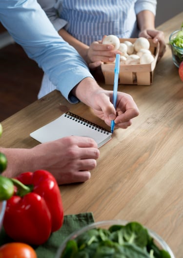 Man en vrouw werken samen aan een laptop en maken aantekeningen in een notitieboek.