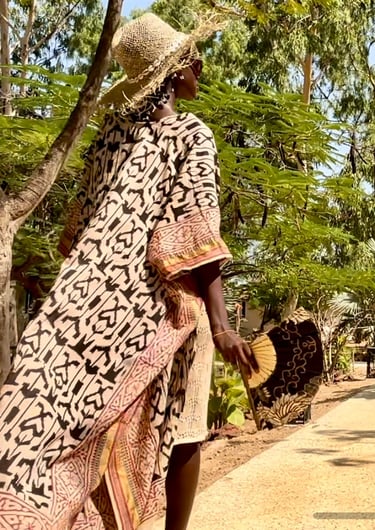 Vue d'une personne marchant dans les allées du boutique hôtel Maison Fimela situé au coeur du Sine Saloum
