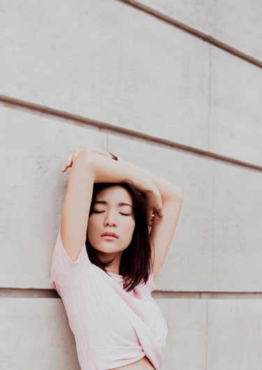 portrait de femme les mains au dessus de la tête adossée contre un mur