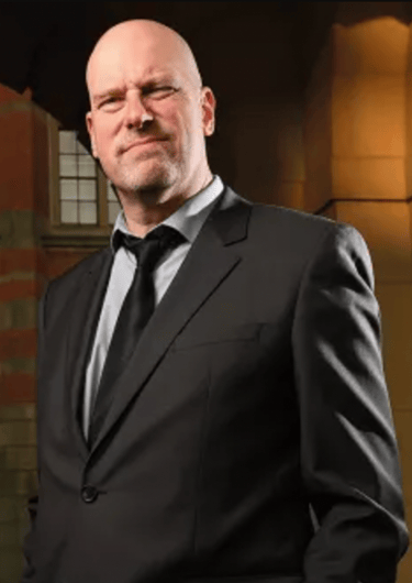 David Gillborn in a suit and tie standing in front of a building