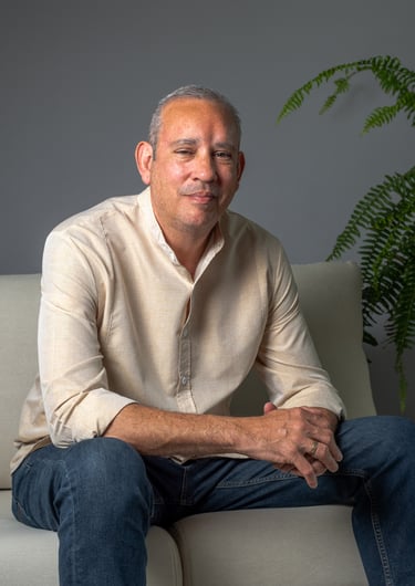 a man sitting on a couch with a plant in the background