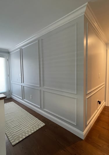 Custom white wall paneling with picture-frame molding and crown molding in a Monmouth County NJ