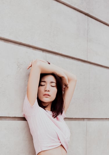 portrait de femme les mains au dessus de la tête adossée contre un mur