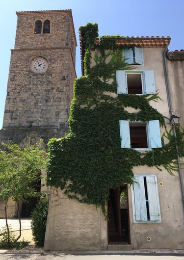 Tour d'horloge historique en pierre jouxtant une maison recouverte de vigne à Quillan Aude.