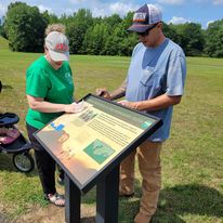 Two FOPM volunteers cleaning state park signage