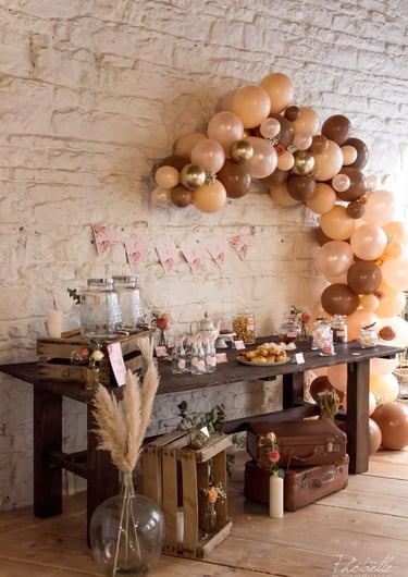 Un mur en brique décoré de ballons et guirlande.Une table avec des bocal à bonbons