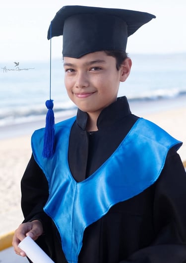 un niño adolescente en una toga en la playa