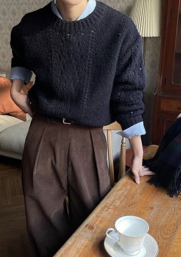 a man in a sweater and pants standing in front of a table