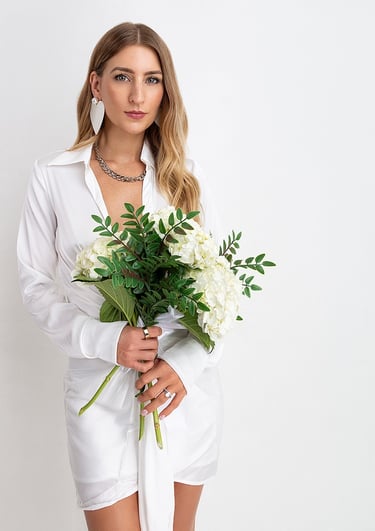 a woman in a white shirt and a necklace with flowers
