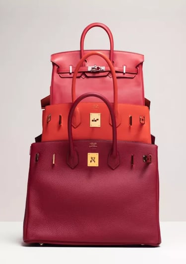 Stacked red and orange luxury Hermes birkin handbags showcasing premium leather craftsmanship.