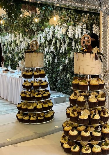 a wedding cake with cupcake tower on a table