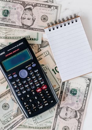 calculator, money, pen, and paper representing making a budget and overall planning finances
