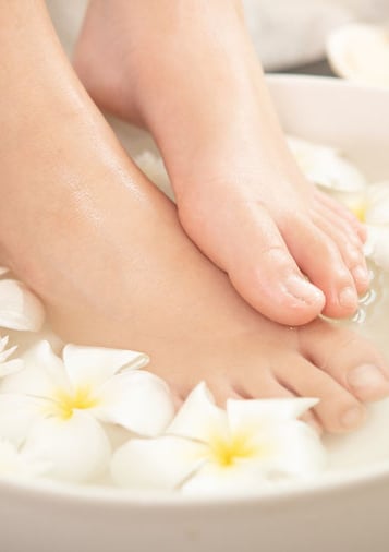 Relaxerend voetenbad met bloemen en natuurlijke oliën bij Medisch Pedicure Grote Berg.