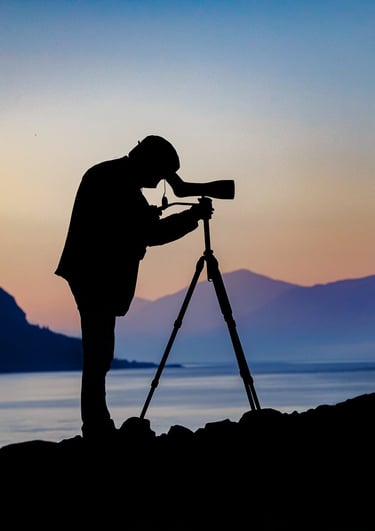 a man standing on a rock with a camera and a tripod