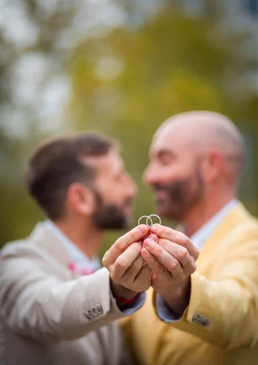 "Pareja gay casada mostrando sus anillos de boda en Madrid, celebrando su amor y unión."