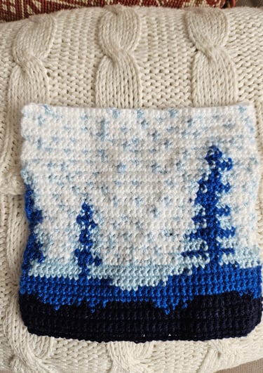 a crochet blue and white tapestry on a white pillow