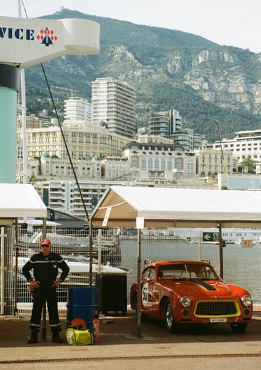 a race car parked in the paddock with a man stood next to it
