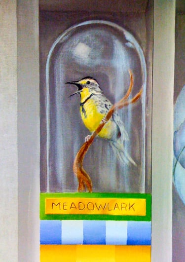 A colourful painting of a bird under a glass globe, placed on stacked books
