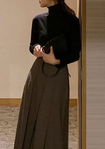 a woman in a skirted skirt and boots standing in front of a door