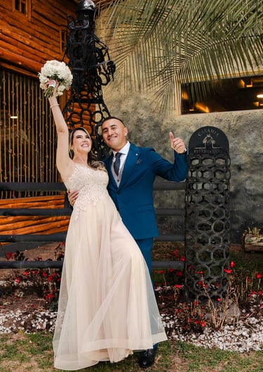 Recién casados celebrando sonriendo a cámara. La novia levanta el ramo y disfrutan de su momento juntos en Quito, Ecuador