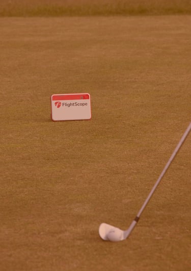 A FlightScope launch monitor being used during a golf lesson on a grassy course in Aberdeen with club positioned for a swing