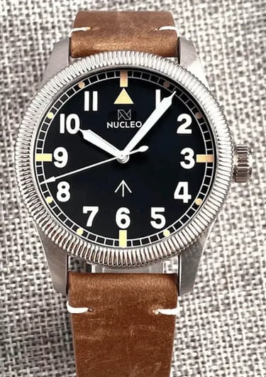 orologio militare field con lunetta fissa scanalata quadrante nero numeri arabi bianchi cinturino cuoio fondo tessuto grigio