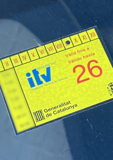 Yellow Spanish ITV inspection sticker on a car windshield valid until 2026 in Catalonia.
