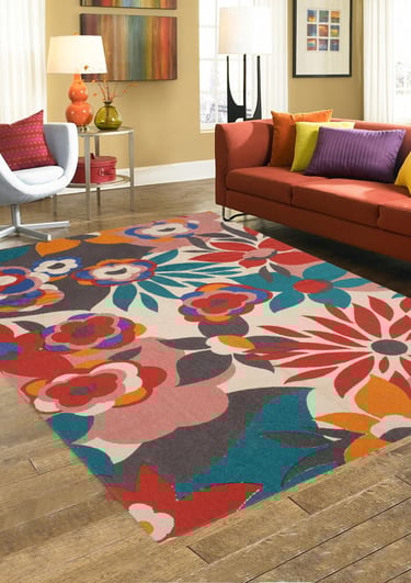 Modern living room with a vibrant floral area rug, orange sofa, and colorful accent pillows.