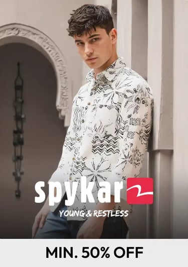 A male model wearing a Spykar patterned white button-down shirt with a black graphic print.