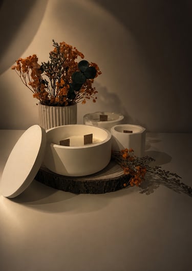 White concrete luxury scented candles with wooden wicks and dried flowers on a rustic wood slice.
