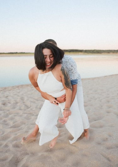 un couple s'amuse et joue lors d'un shooting couple sur des tons pastel plage du Veillon en Vendée