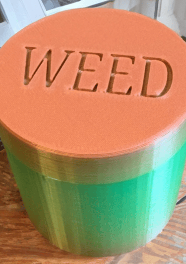 barattolo per la cannabis verde e tappo arancione con la scritta weed incisa