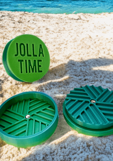 grinder color verde sfumato verso il blu, posato sulla spiaggia
