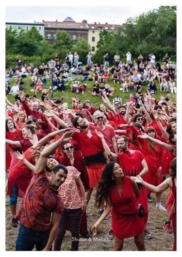 Eine fröhliche Menschenmenge in roter Kleidung tanzt im Görlitzer Park.
