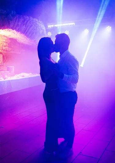 Danse d'un couple sous lumières colorées et ambiance festive en soirée de mariage.