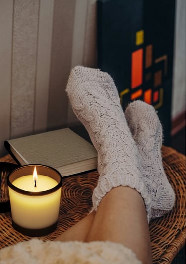 feet in cozy socks on a table, naked legs, candle, notebook, comfy. used socks.