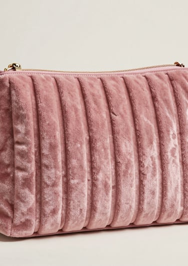 A green clothes hanger holds a perforated white garment with textured material. Slight colorful stitching is visible on the fabric, which features numerous small holes.