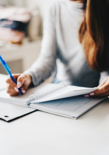 Woman is writing something on a notebook